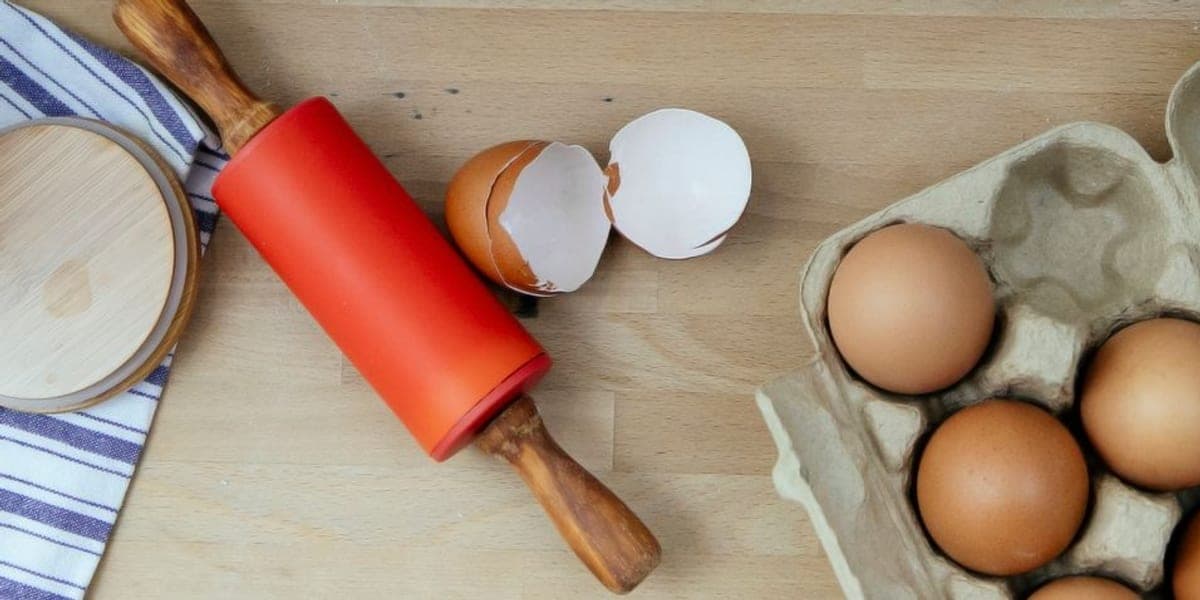 Brown eggs in an open carton on a wooden kitchen worktop